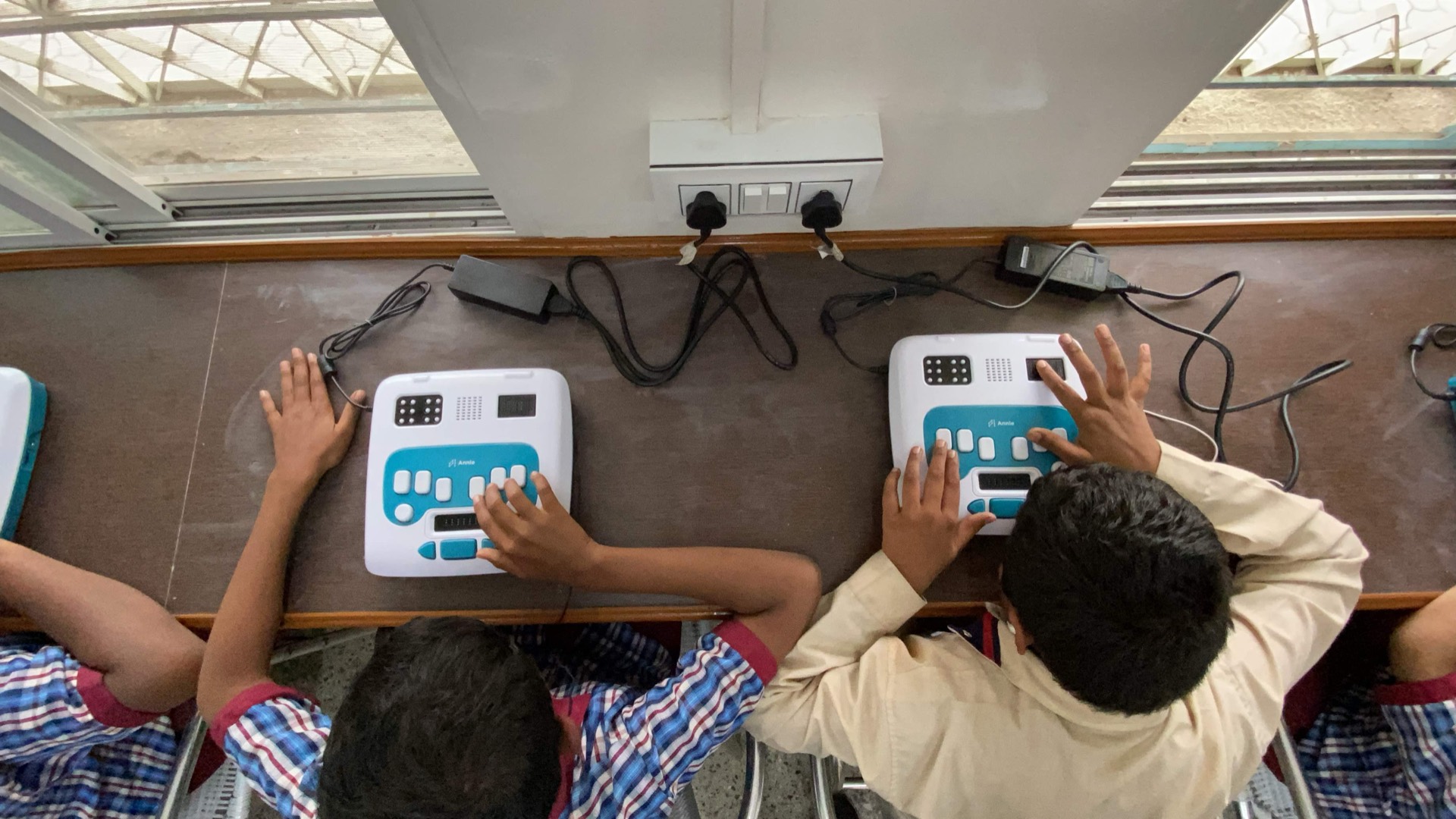 A learner reading braille with both hands on Annie